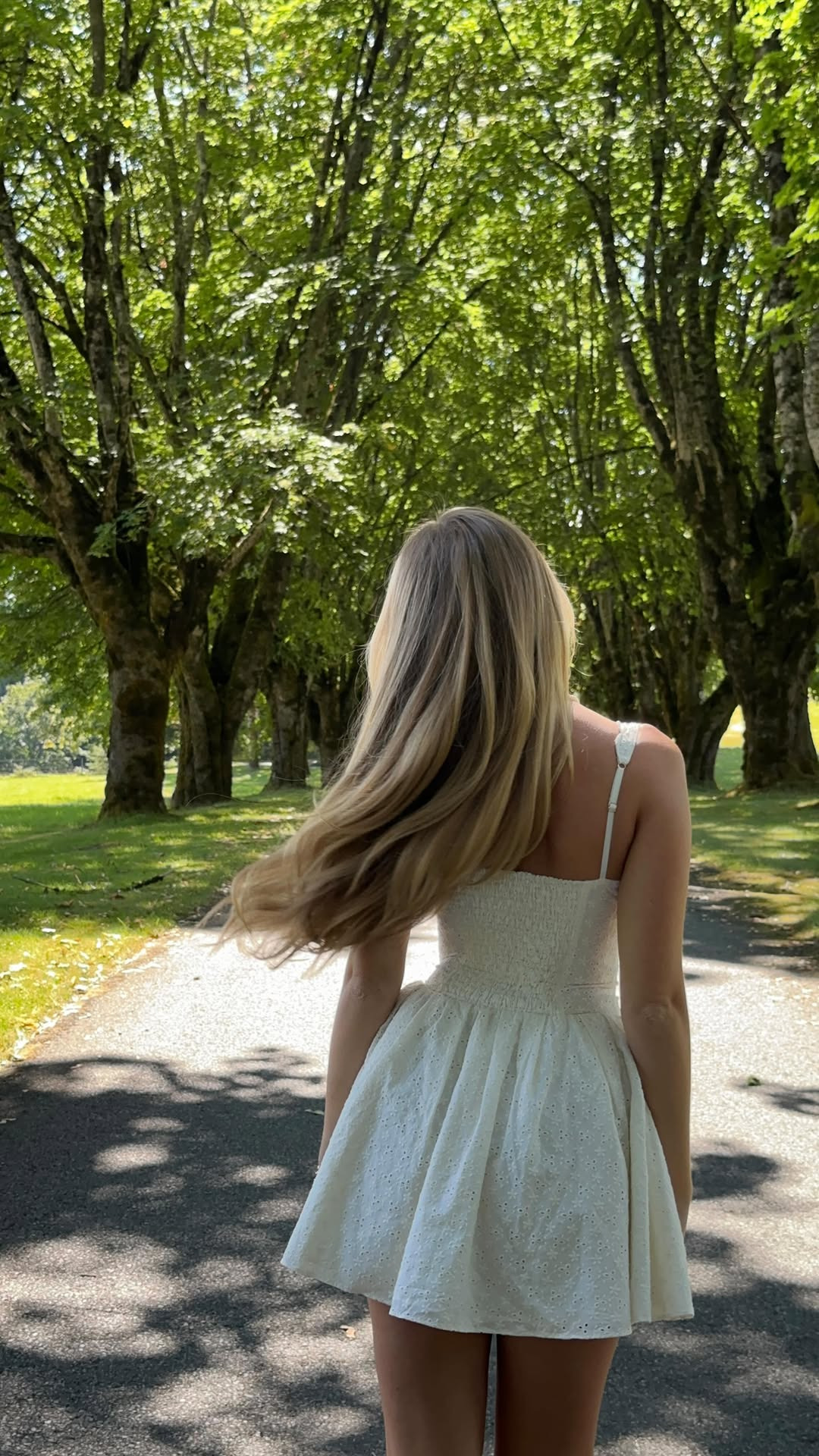 Nika walking beneath tall trees in the countryside